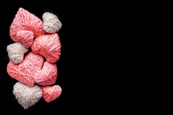 手工粉红色和白色羊毛纱心脏被隔离在黑色 许多粉红色和白色的心编织线程背景与 Copyspace 爱的象征 爱情和浪漫概念 — 图库照片