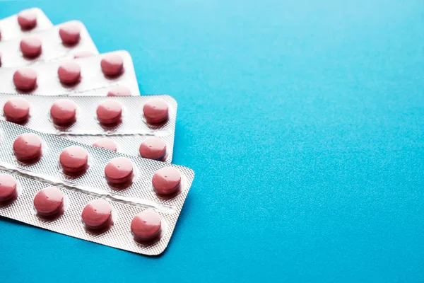 Kabarcıklar mavi bir arka plan üzerinde pembe tablet. Simli kabarcıklar hap birçok paket. Statinler, enzimler, ilaçlar, antibiyotik. Uzay kopyalayın. Sağlıklı, eczane ve sağlık kavramı