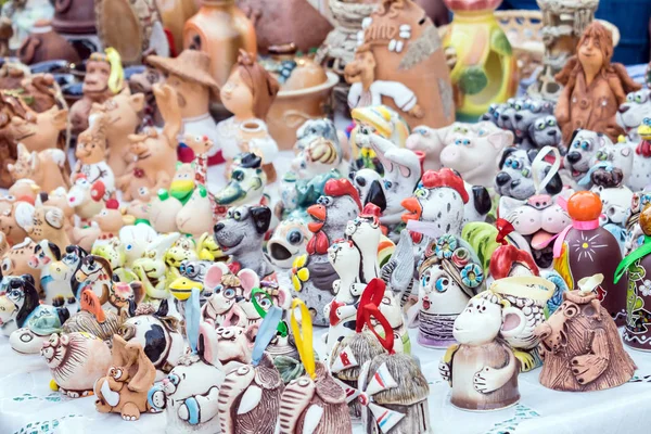 Colorful cute souvenir decorative clay bells, wind chimes, toys, dolls, figurines of animals and people. Handmade souvenir ceramic at the market, traditional craft