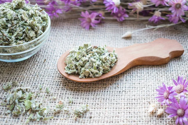 Coltsfoot (Tussilago farfara L.) tahta kaşık çul arka plan üzerinde bir kesim kuru yapraklar. Uyuşturucu (Farfarae folium) tedavisi akciğer sorunları için: bronşit, astım, boğmaca. Bitkisel alternatif tıp. 