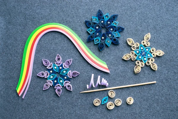 Noel el sanatları kağıt şeritler gelen kar taneleri şeklinde quilling kağıt. Araç ve gereçleri üzerinde gri bir DIY quilling Noel için arka plan hissettim. Noel süsleri gazeteden oluşturma işlemi
