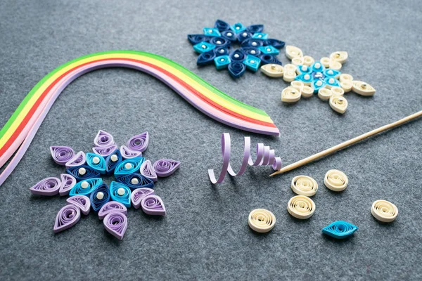 Noel el sanatları kağıt şeritler gelen kar taneleri şeklinde quilling kağıt. Araç ve gereçleri üzerinde gri bir DIY quilling Noel için arka plan hissettim. Noel süsleri gazeteden oluşturma işlemi