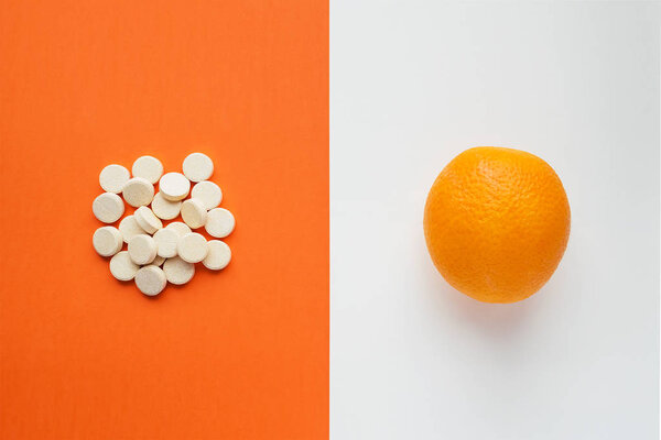 Vitamin C concept in minimalist style. Natural vitamin  in orange vs synthetic vitamin  in pills. Choice between natural and synthetic way of health care. Dietary supplement