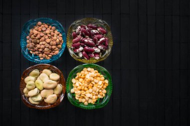 Fasulye ve mercimek siyah ahşap arka plan üzerinde renkli cam yemekler farklı tür. Diyet, kilo kontrolü ve diyabet için faydaları. Fasulye faydaları sağlık.