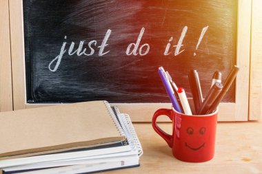 Inspirational alıntı yazı sadece Do It kalemler ve kurşun kalemler, kırmızı Kupası ile siyah kara tahta üzerinde kazık bloknot ve kağıtları. Motivasyon iş ofis arka plan. Erteleme yenmek nasıl