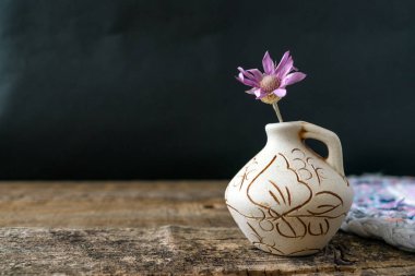 Bir eflatun çiçek Xeranthemum kil vazo ahşap doku arka plan üzerinde üzerinde yakın çekim. Wabi Sabi, Hygge, Lagom tarzı. Yalnızlık, basitlik, Minimalizm kavramı. Kopya alanı