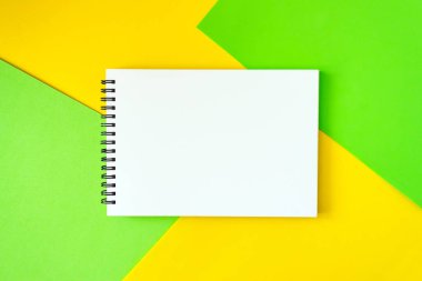 Minimal, pop sanat, Soyut, canlı mockup parlak yeşil ve sarı zemin üzerine beyaz Not defteri ile. Bir tabloda üstten görünüm açık sarmal boş defter. Düz yatıyordu