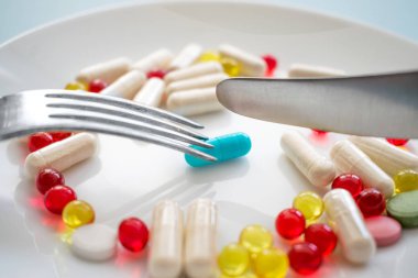 İlaç tıp hap, tablet ve kapsüller ve bıçak ve çatal plaka üzerinde bir mavi Kapsül çeşitli. İlaç gıda olarak, diyet takviyeleri. Opioid salgın, uyuşturucu kullanımı ve aşırı doz kavramı