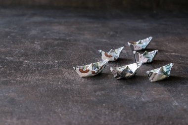 US Dollar paper boat on dark background. Many Ships from a money, Origami paper boats from dollars banknote on dark table. Financial, business concept. Selective focus clipart