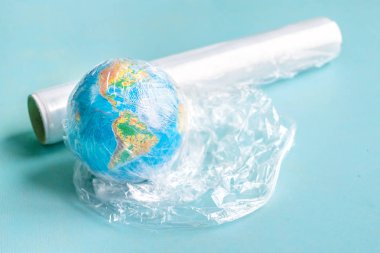 Fiziksel dünya, dünya top plastik wrap kopya alanı ile mavi arka plan üzerinde. Dünya Çevre Günü kavramı. Plastik toprakla kirliliği ile çevre sorun çözme