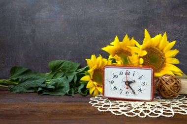 Sonbaharda hasat Sonbahar zaman, tebrik kartı kavramı. Natürmort güzel ayçiçeği, kırmızı saat, ahşap rustik zemin üzerine dantel peçete.