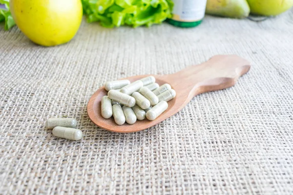 Homeopatik ek kapsül içinde tahta kaşık. Alternatif Tıp. Vitamini kapsülleri. Salmonella kusurlu bitkisel