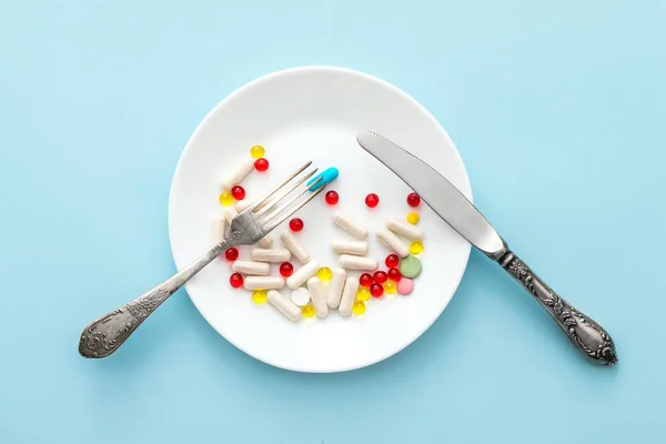 Many different weight loss pills and supplements as food on round white plate with fork and knife. diet pills and supplements, prescription weight loss drugs, appetite suppressants for dieting concept