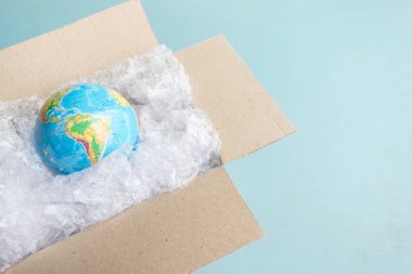 Fiziksel dünya, kopya mavi zemin üzerine karton kutuda plastik wrap Earth'te uzay Recyclable ekoloji sorun çevre kirliliği gezegenin ambalaj plastik dünya gün dünya çevre günü tarafından