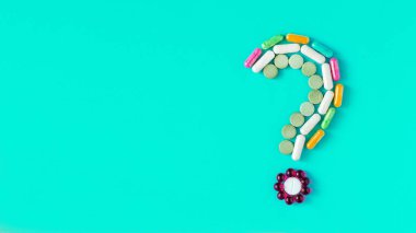 Farklı renkli hap, tablet ve kapsüller mavi zemin üzerine soru işareti yaptı. İlaç endüstrisi ve reçete en az kavramı afiş. Düz yatıyordu, en iyi görünümü, 