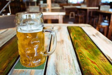 Gözlük pub arka plan üzerinde hafif bira. Aperatifler ve barda, ahşap masa üzerinde ızgara gıda ile altın bira bira cam bar