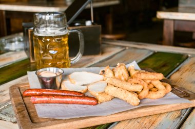 Gözlük pub arka plan üzerinde hafif bira. Aperatifler ve barda, ahşap masa üzerinde ızgara gıda ile altın bira bira cam bar