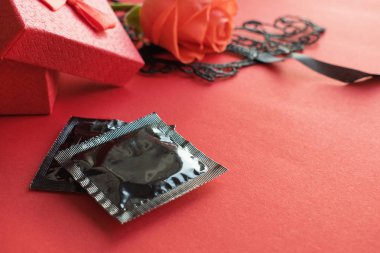 Aşk, tutku, seks romantik düz yatıyordu, kırmızı gül, siyah dantel karnaval maskesi, hediye kutusu ve kırmızı zemin üzerine iki prezervatif ile sahte. Güvenli seks, kavram dating.
