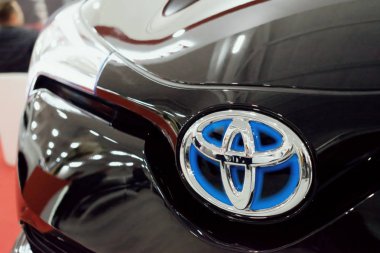 Siyah araba mavi Toyota logosuna kadar kapatın. Toyota Hybrid modelleri kullanılan mavi arka plan ile özel marka logosu.
