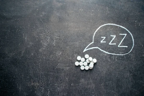 White pills in Z shape and text. Sleeping pills, hypnotic drugs, sedative, melatonin on dark night background