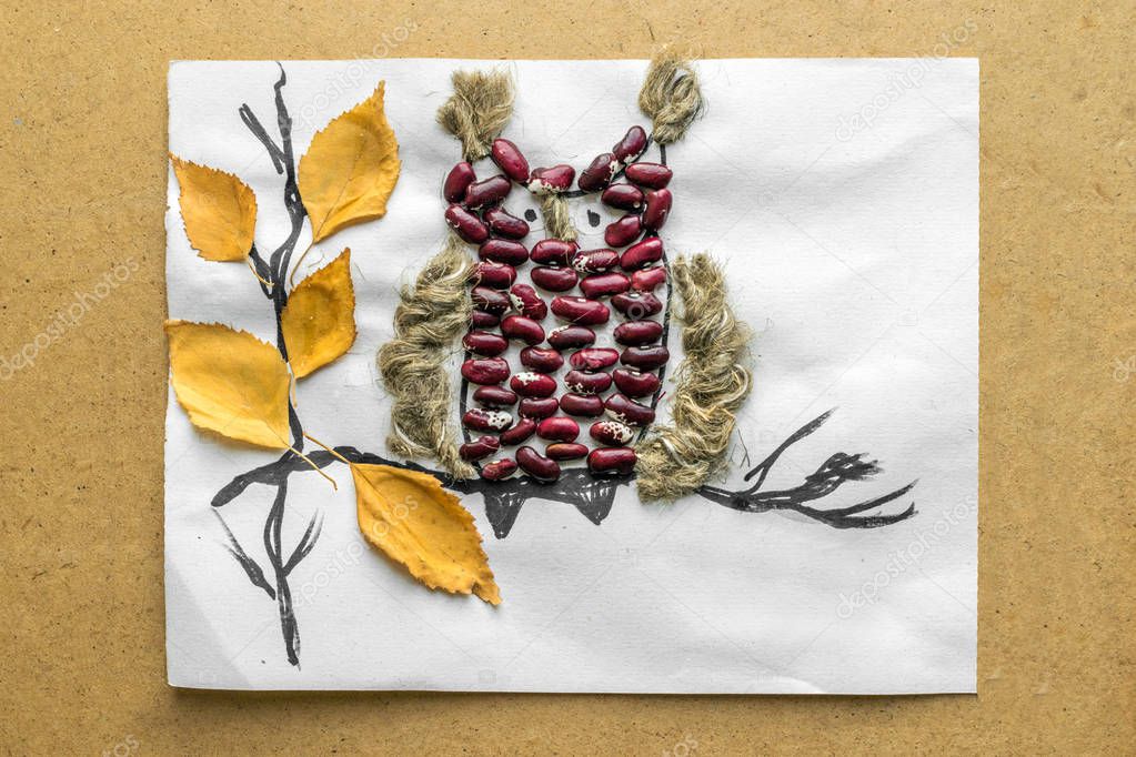 Funny owl from cereals, beans, dried leaves and colored paper Children's seasonal crafts from natural materials. Original children's art project. DIY creative handmade concept.