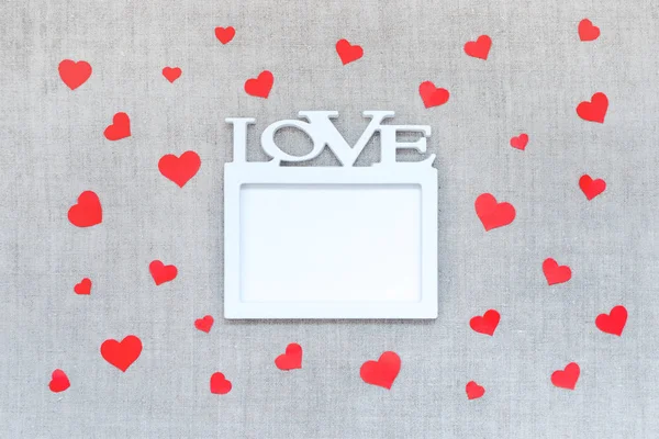 Valentines Day mockup with white frame with word LOVE and many red hearts on linen fabric background.  Valentine Day, love, romance, dating concept, copy space