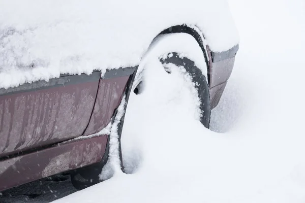 Car wheel with winter tires stalled in the snow. Wheel stuck in a snowdrift. Snow drifts on road, bad weather
