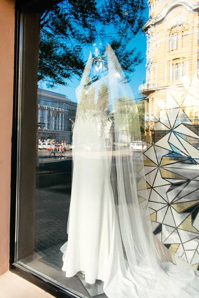 Female mannequin in wedding dress in showcase. Bridal dresses Salon Showcase window display with reflections of the sky and buildings