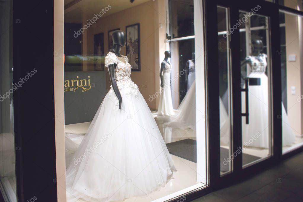  Black female mannequin in wedding dress in showcase. Bridal dresses Salon Showcase window display with light in night