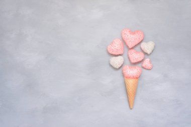 Dondurma waffle koni gri çimento zemin üzerine pembe ve beyaz iplik kalp ile. Sevgililer günü tebrik kartı kopya alanı ile. En az stil, düz yatıyordu