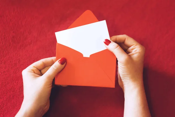 情人节贺卡 模型与复制空间 女性手与空的白卡和红色信封在红色背景 最小的样式 — 图库照片