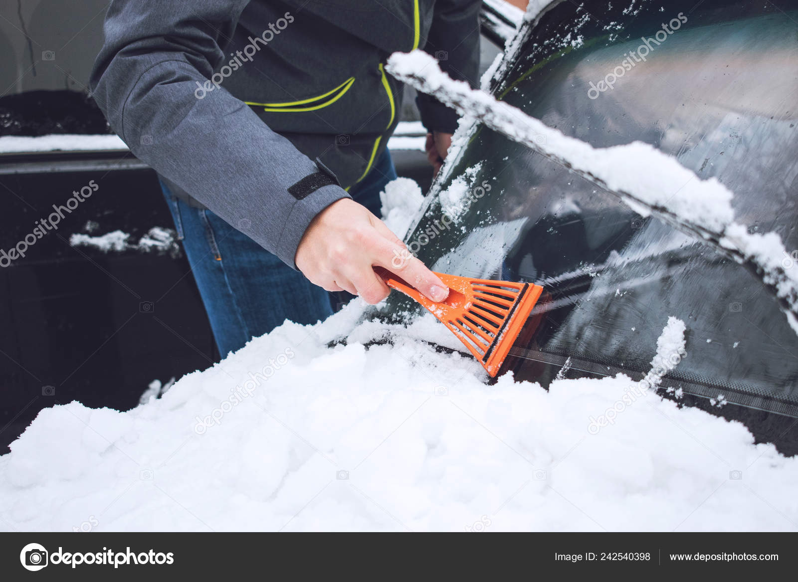 在降雪过程中男子用刷子和刮刀清洗汽车从雪和冰中清洗冬季紧急情况与天气有关的车辆紧急情况被雪覆盖的汽车