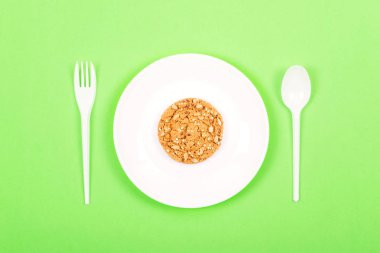 Beyaz tabak kaşık, çatal ve bütün tahıl çerezleri yulaf ezmesi. Ketogenic diyet, kilo kaybı, aralıklı oruç, öğle vakti kavramı. En az stil, düz yatıyordu, en iyi görünümü.