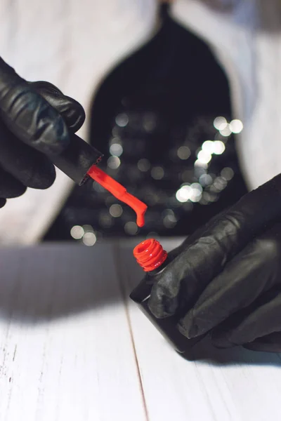 赤エッジのボトルを保持黒手袋のマニキュア専門家 — ストック写真