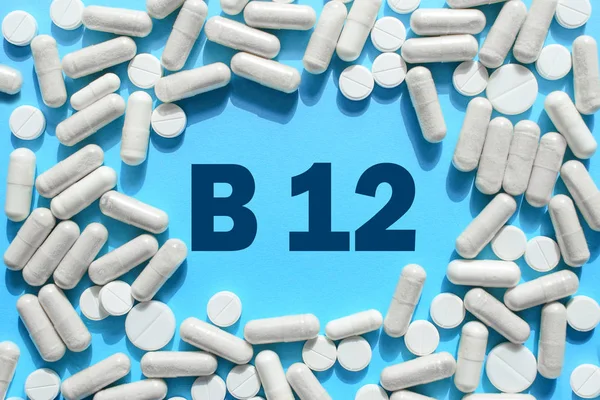 Texto de vitamina B12 em cápsulas brancas moldura em fundo azul. Pil — Fotografia de Stock
