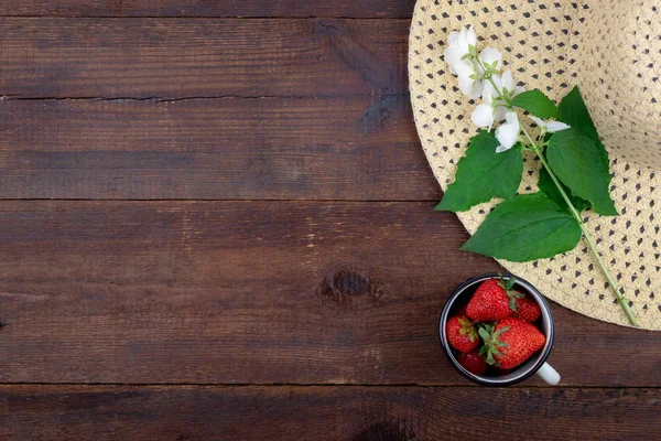 Summer background with straw hat, strawberries in cup and white