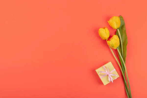Tulipanes amarillos flores, caja regalo n fondo coral. Birt festivo — Foto de Stock