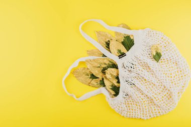 Yeşil ve sarı yapraklı yeniden kullanılabilir alışveriş çantası.