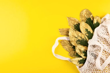 Yeşil ve sarı yapraklı yeniden kullanılabilir alışveriş çantası.