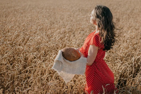 Portrait of happy young woman in red dress holding rustic rye br — Stok Foto