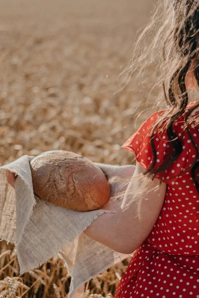 Portrait of happy young woman in red dress holding rustic rye br — Stok Foto