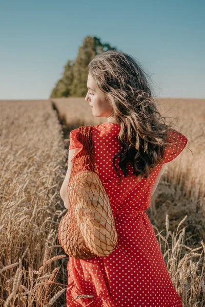 Mujer joven feliz en vestido rojo con pan y mocasines en el groce neto —  Fotos de Stock