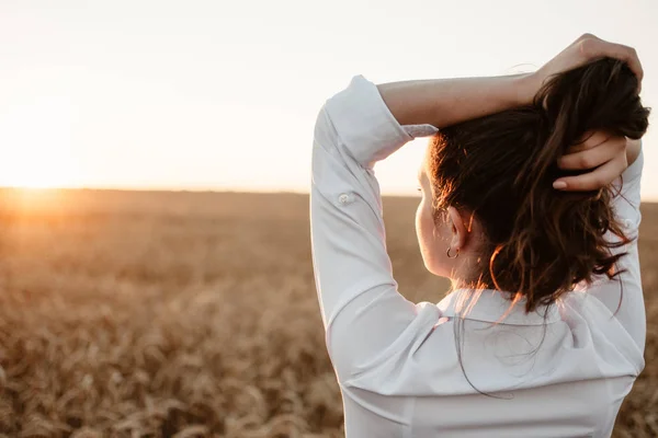 Giovane ragazza nel campo di grano al tramonto. Bruna dai capelli ricci bianca — Foto Stock