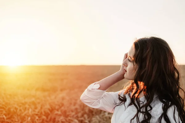 Giovane ragazza nel campo di grano al tramonto. Bruna dai capelli ricci bianca — Foto Stock