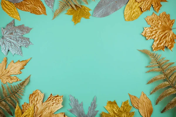 Autumn composition with golden leaves frame on blue mint backgro