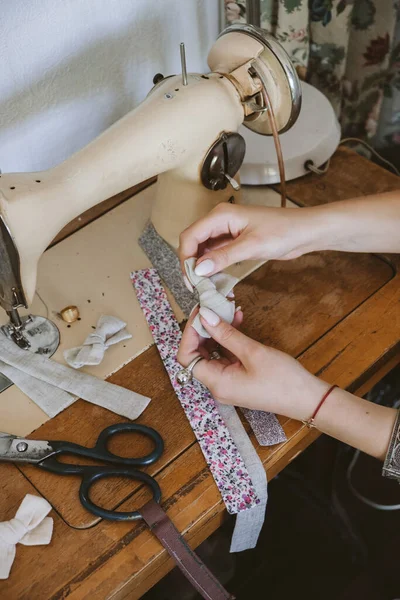 Small business ideas, seamstress local business, vintage dressmaker workspace. Female fashion designer making craft fabric hair accessories, bow, hairpins. Tailor working at desk with sewing machine.