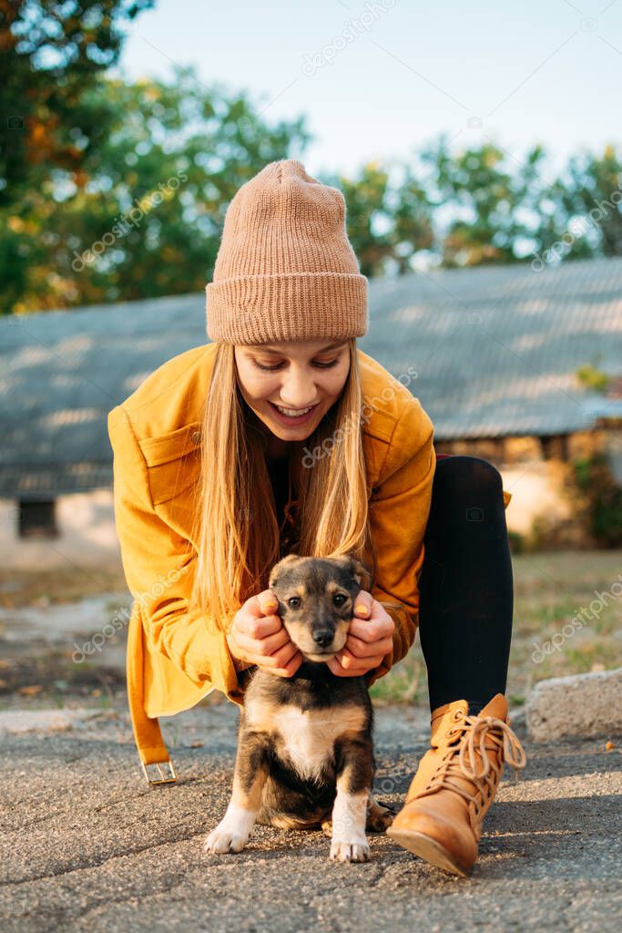 World Animal Day. Woman Volunteer meeting homeless dog puppies in fall nature background. Pet love, caring for a pet and animal adoption concept.