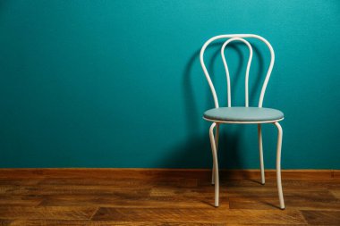 Tasarımda minimalizm, yenileme. Minimalist Apartman Dekoru. Beyaz sandalye boş mavi duvara dayanıyor. İçi boş oturma odasının fotokopi alanı var..