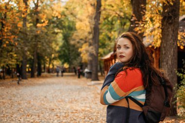 Sonbahar seyahati, sonbahar gezisi, kaçış, tatiller, tek başına seyahat. Artı sonbahar parkında sırt çantalı bir kız..