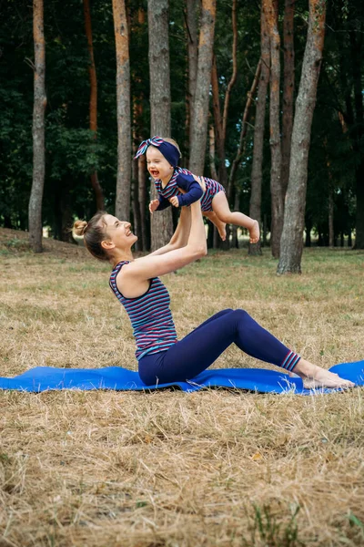 Mom and baby yoga outdoor. Wellness, family yoga class, practicing mindfulness and meditation, physical and mental health concept